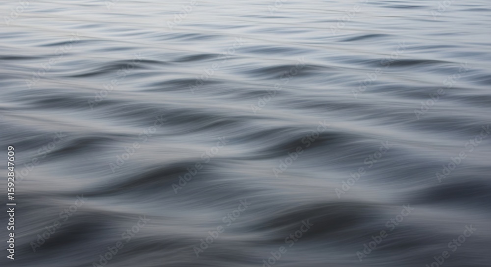 Naklejka premium Close-up view of water surface with gentle waves creating a soft, blurred effect.