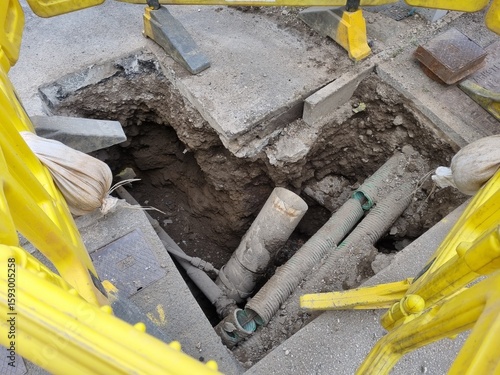 Construction site with exposed pipes, revealing infrastructure work and repairs on a city street.