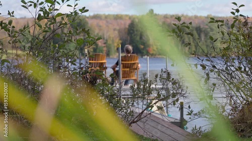 Soft focus autumn view of a man relaxing on an adirondack chair by the lake