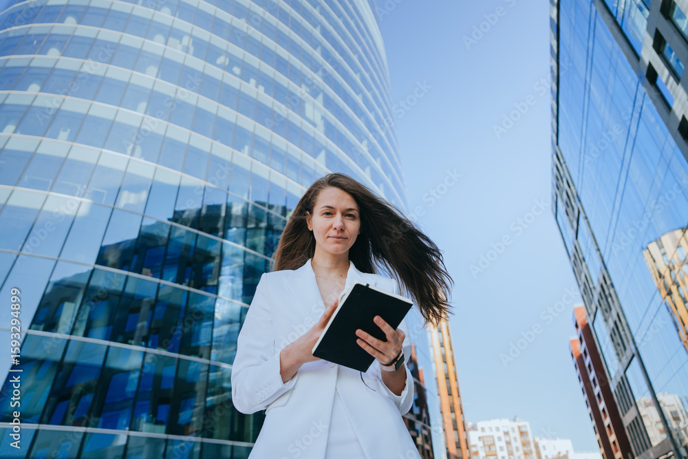 Fototapeta premium A joyful woman with outstretched arms radiates excitement in front of a sleek glass building, embracing a new day.
