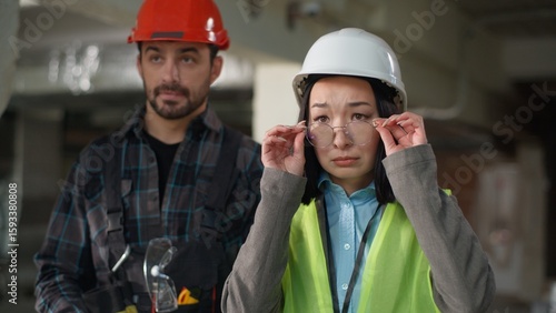 Multiethnic engineers disagreement reaction Japanese business woman inspector take off glasses disapprove bad project construction Caucasian man confused site misunderstanding inspection issue tension