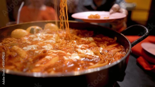 A steaming pot of spicy korean tteokbokki with noodles and cheese