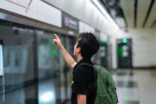Canvas Print The image shows a young man, wearing a backpack, pointing at a map or informatio