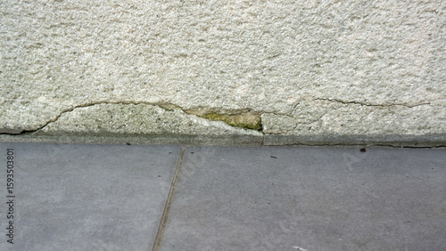 Crack and water damage at the base of an exterior concrete wall