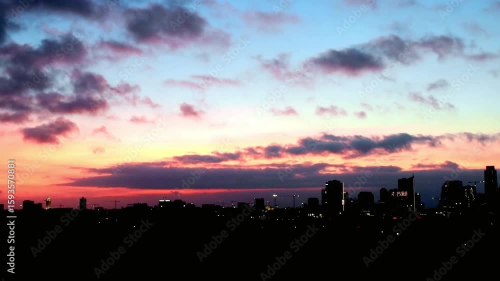 A dramatic sunset sky over a dark city skyline at night A dramatic sunset sky over a dark city skyline at night