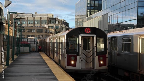 train arriving on platform in court square queens long island city new york nyc famous outdoor elevated station stop seven 7 metro commuter line tall buildings in background tracks railroad track