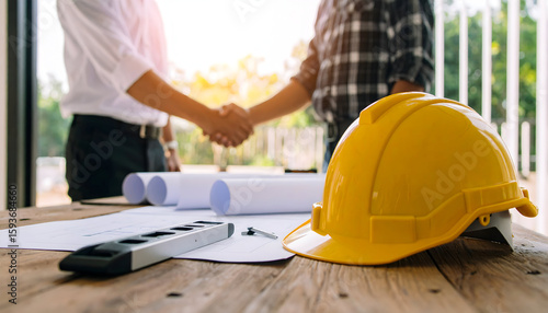 Construction workers in yellow hardhats and safety gear diligently work with tools at a bustling industrial building site