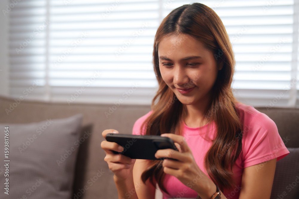 Asian young adult woman playing mobile game smartphone technology lifestyle home sofa casual entertainment online hobby digital connectivity Asian young adult woman playing mobile game smartphone technology lifestyle home sofa casual entertainment online hobby digital connectivity