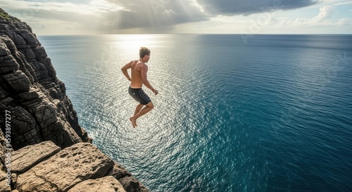 Man jumps off cliff into the ocean on a sunny day adventure