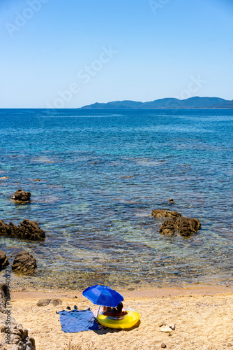 Wallpaper Mural Relaxing on inflatable mattress under beach umbrella at Capo Ferrato, Sardinia Torontodigital.ca