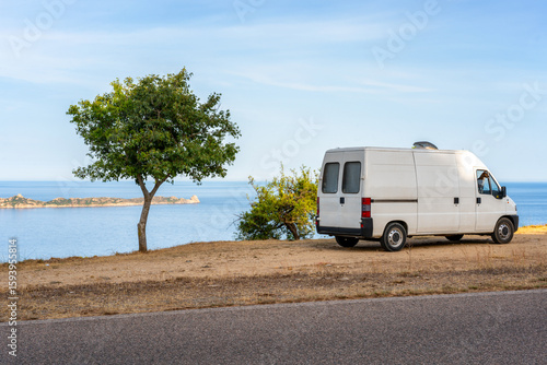 White camper van parked near the coast in Sardinia, Italy enjoying summer holidays