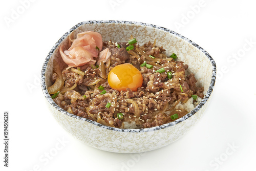 Bowl of gyudon, Japanese beef rice dish, topped with raw egg yolk, sesame seeds, and green onions, served with pickled ginger in ceramic bowl