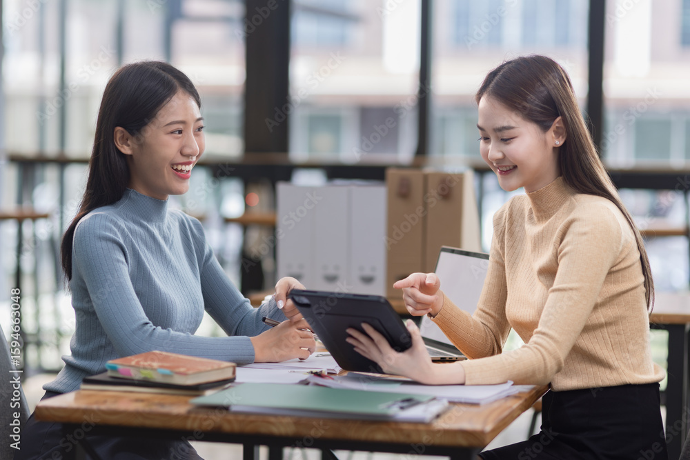 Two young Asian businesswoman and looking at digital tablet company device in office. Two young Asian businesswoman and looking at digital tablet company device in office.