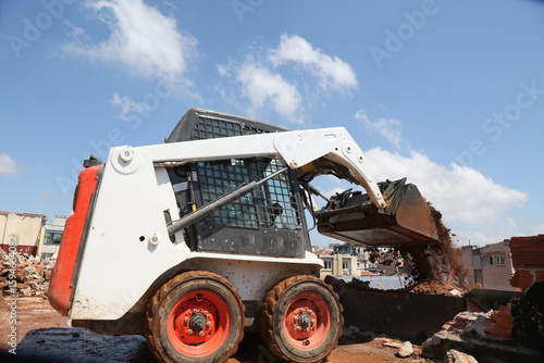 skid steer loader working construction site. mini loader transports excavation waste at construction site. compact loader. skeed steer workingi on site. compact construction machinery.