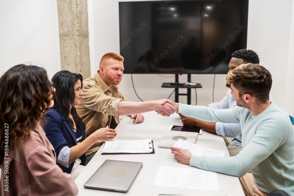 Obraz premium Coworkers shaking hands after reaching an agreement during a business meeting in a modern coworking office