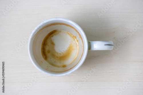 Close-up of an empty white ceramic mug with residual coffee or tea stains, viewed from above. Perfect for beverage, morning, or kitchen concepts, highlighting realistic used drinkware.