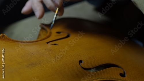 Fotografie Skilled craftsman varnishing wooden cello, meticulously brushing lacquer surface
