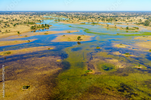 Breathtaking aerial view of the Okavango Delta near Maun in Botswana, showing vibrant wetlands, blue lagoons, and golden grasslands. Ideal for use in nature, travel, and wildlife photography projects.