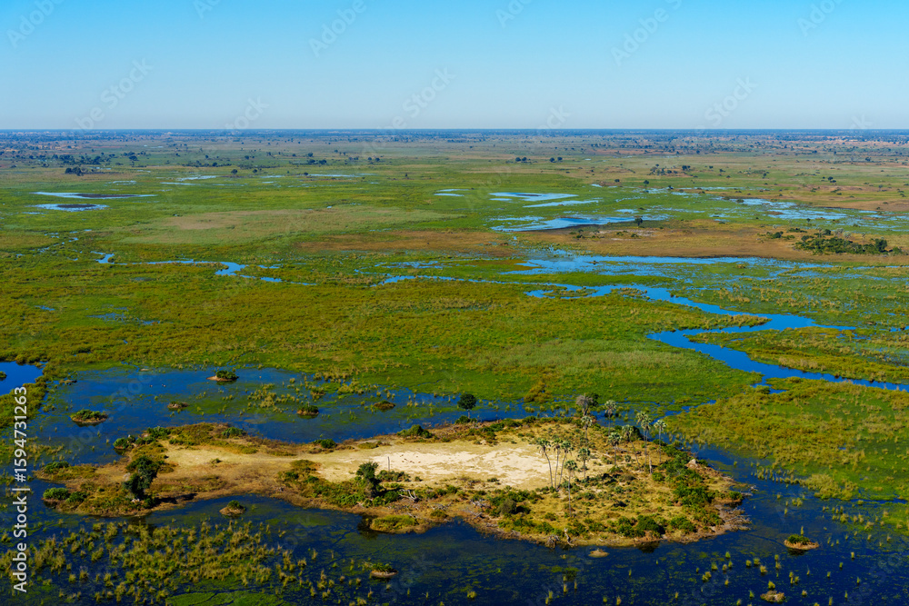 Obraz premium Breathtaking aerial view of the Okavango Delta near Maun in Botswana, showing vibrant wetlands, blue lagoons, and golden grasslands. Ideal for use in nature, travel, and wildlife photography projects.