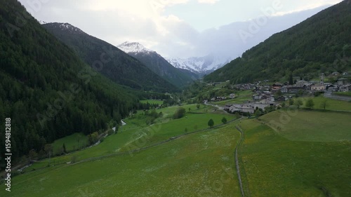 Breathtaking mountain village surrounded by lush valleys and snow-capped peaks during a tranquil afternoon