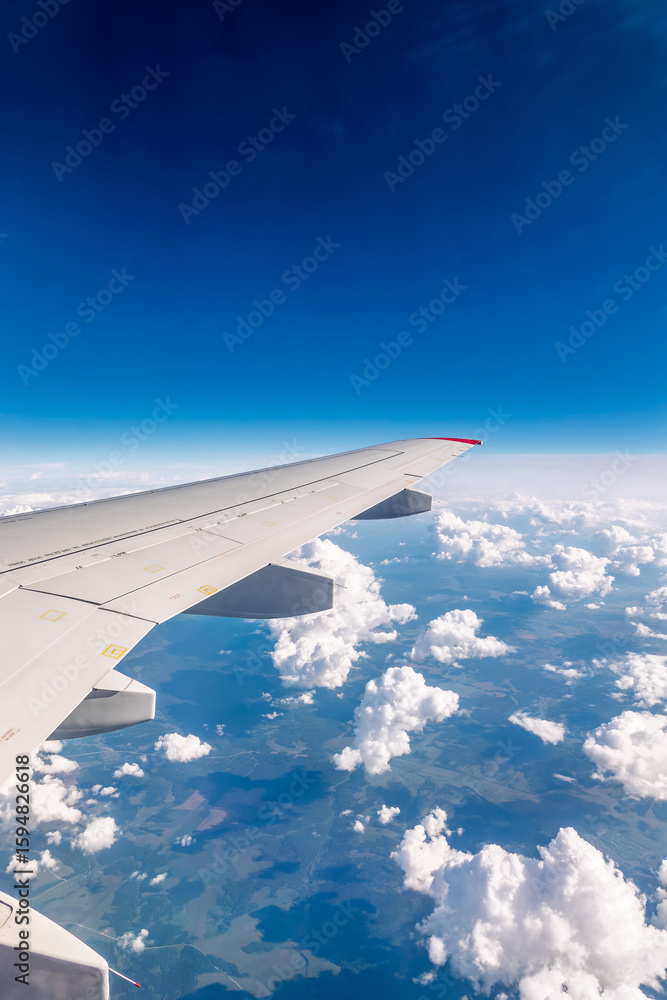 Fototapeta premium View from the airplane window at a beautiful cloudy sky and the airplane wing