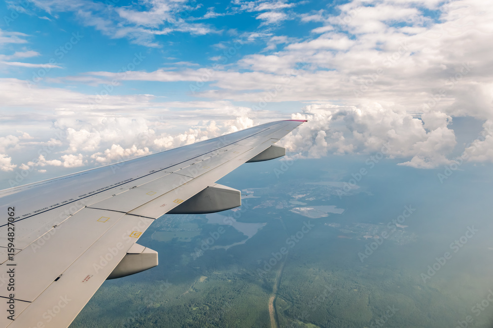 Obraz premium View from the airplane window at a beautiful cloudy sky and the airplane wing