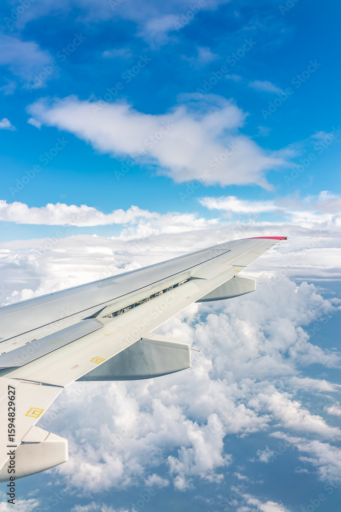Fototapeta premium View from the airplane window at a beautiful cloudy sky and the airplane wing