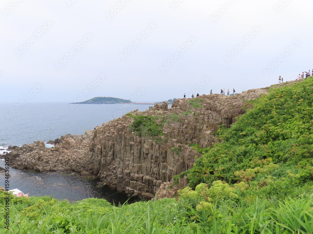 Fototapeta premium Tourists walking along rugged cliffs of Tojinbo on Japan Sea coast