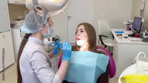 Examination of the oral cavity of a young woman by a woman's dentist.video