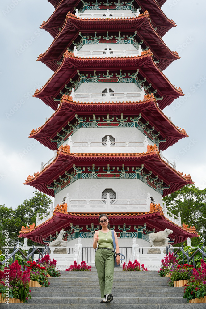 Fototapeta premium young woman stands on the steps leading up to a multi-tiered traditional Chinese pagoda