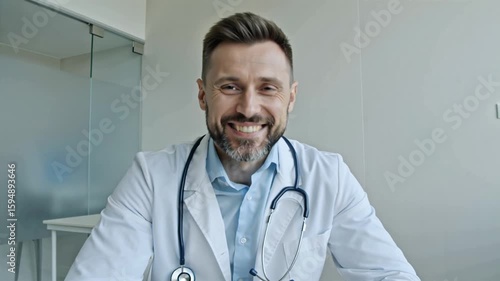 A friendly doctor in a white coat smiles warmly, speaking with reassuring gestures.