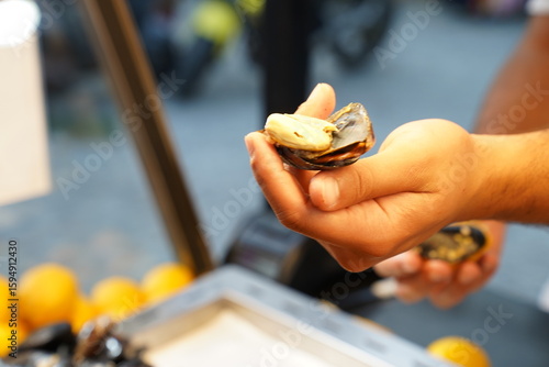 A man is opening stuffed mussels with his hand
