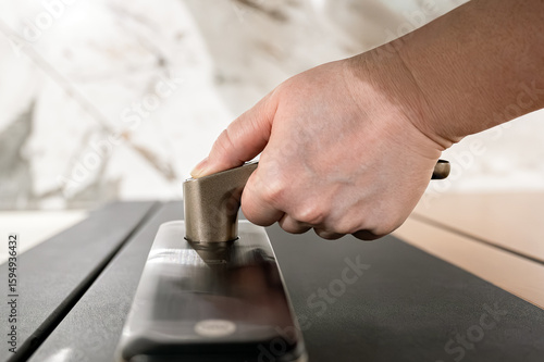Close-up of female hand pressing fingerprint sensor on smart lock, concept of biometric authentication and smart home entry