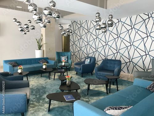 Contemporary hotel lobby featuring elegant blue sofas and modern silver statement lighting — a stylish, tranquil space reflecting high-end hospitality design