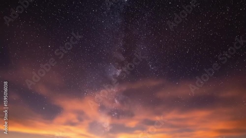 A breathtaking sunset over mountainous terrain, with vibrant clouds illuminated by the fading sun, showcasing a serene transition into night as stars begin to appear in the sky