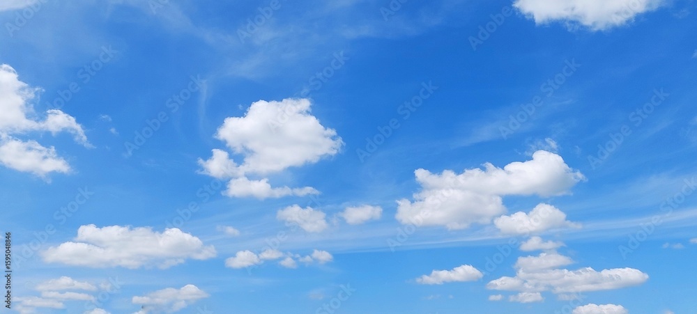 Naklejka premium Soft white clouds with a beautiful blue sky in the morning light. Soft white clouds float in the clear blue sky. Clear blue sky, bright spring, soft sky gradient.