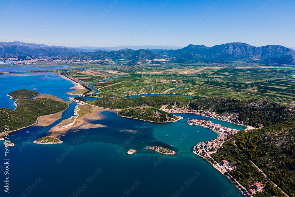 Obraz premium Aerial panorama of Blace village and Neretva River delta, showing coastline, green valley, and turquoise Adriatic Sea under clear summer sky