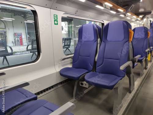 Modern train interior featuring spacious blue seats with ergonomic design, showcasing a clean and comfortable travel environment with ample natural light