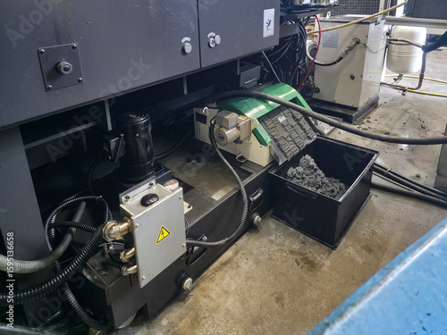 Industrial machinery operating in a workshop with various components and materials present while a maintenance activity takes place