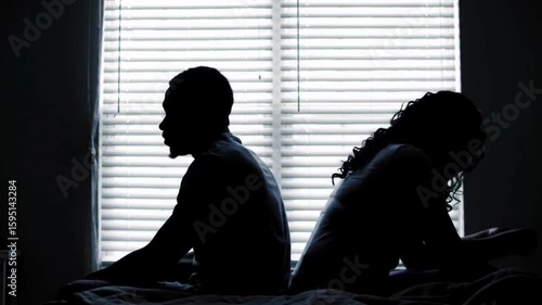 A couple quarreling concept of family relationship problems divorce, black silhouette of man and woman sitting at bed back to back resentment towards each other window in dark room
