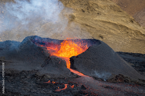 Close-up image of the violent lava eruption of Fagradalsfjall Volcano, which has erupted several times, near the town of Grindavík in southwestern Iceland. There are hills in the background.