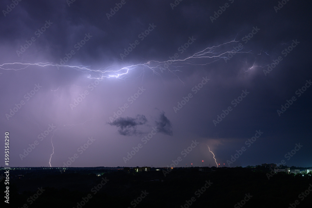 Fotografie Horizontal lightning flashes across a purple night sky