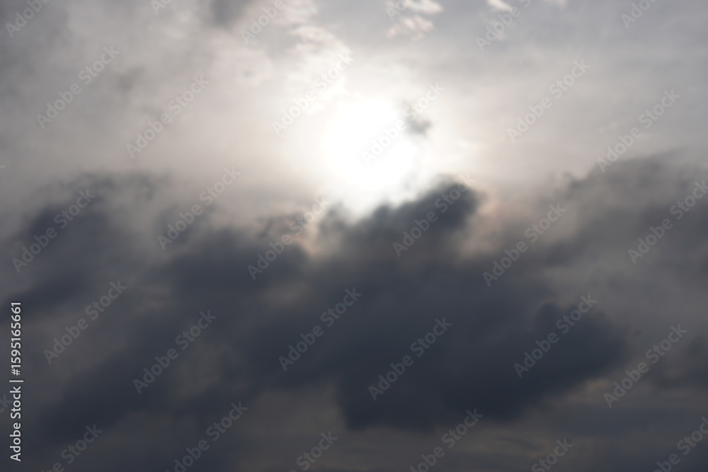 Obraz premium A sky with a bright sun, partially obscured by dark clouds