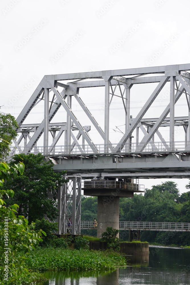 Fototapeta premium Steel Truss Railway Bridge Over River – Infrastructure in Natural Setting