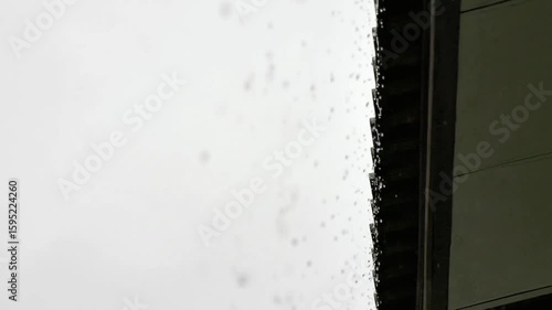 Raindrops falling from the eaves of a roof during a storm