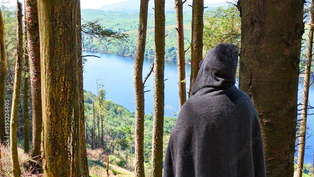 Obraz premium Mysterious cloaked character watches a lake from the shadows of woodland. Ideal for dark fantasy concepts