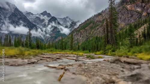 Majestic Mountain Range with Cloud Cover Over Conifer Forest and River Scene in Natural Landscape