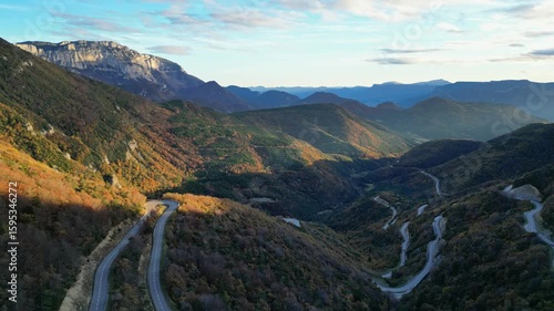  Winding mountain road in Vercors seen from Col de Rousset at sunset, cars driving through forested slopes in Drome region, southeastern France