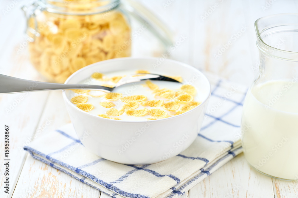 bowl of tasty corn flakes with milk on a light kitchen table. bowl of tasty corn flakes with milk on a light kitchen table.