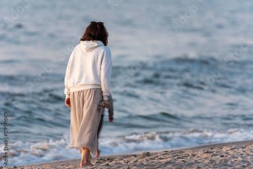 Fototapeta Naklejka Na Ścianę i Meble -  The woman walking on a sandy beach at evening. Poland, Baltic Sea during summer time.